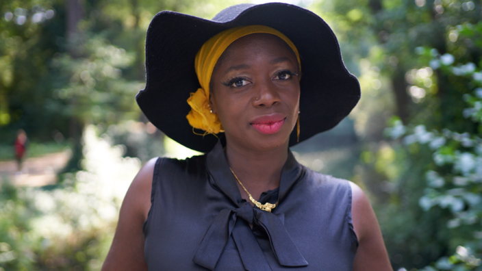 Portrait: Maimouna Coulibaly looks into the camera, she is wearing an elegant hat and lip stick