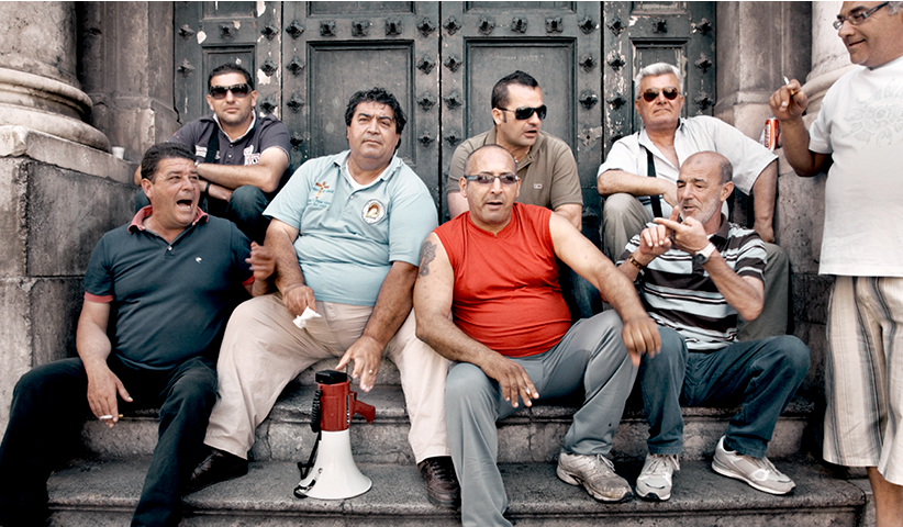 Unemployed men wait in front of the city hall of Palermo ahead of a demonstration