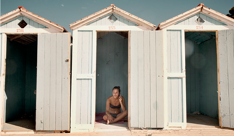 Eine junge Frau telefoniert in einer Umkleidekabine am Strand von Mondello auf Sizilien