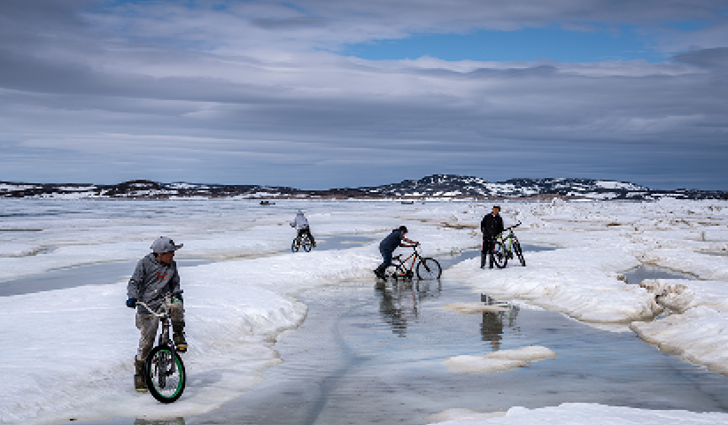 Nach einem langen, dunklen Winter fahren Kinder der Inuit-Siedlung Cape Dorset im Bundesstaat Nunavut mit ihren Fahrrädern durch den schmelzenden Schnee